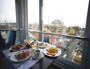 a table with two plates of food and a window at Merial Hotel Sultanahmet in Istanbul