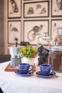 a table with two blue cups and a vase with flowers at B & B La Terrazza sul mare in Portoferraio