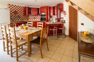 cocina con mesa de madera y armarios rojos en Dairy Cottage, en Ayr