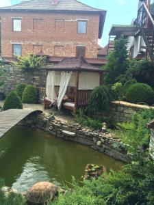 a house with a pond in front of a building at Guesthouse Grand Canyon in Kamianets-Podilskyi
