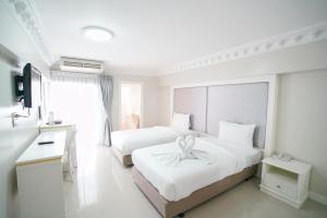 a white bedroom with two beds with a ribbon on it at Romance Hotel Sukhumvit 97 in Bangkok