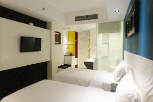 um quarto de hotel com duas camas e uma televisão em Karebosi Premier Makassar em Macáçar