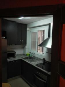 cocina con armarios negros, fregadero y ventana en Apartamento En Benidorm, en Benidorm