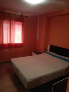 1 dormitorio con 1 cama y una ventana con cortinas rojas en Apartamento En Benidorm, en Benidorm