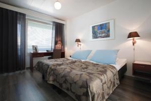 a bedroom with a bed and a desk and a window at Hotel Milton in Jyväskylä
