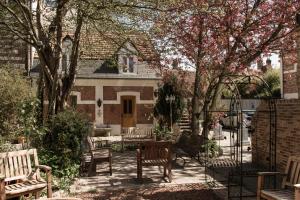 a patio with benches and a table in front of a house at Coq hôtel in Montreuil-sur-Mer