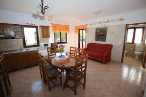 a kitchen and dining room with a table and a red couch at Villa Linet Garden in Funtana