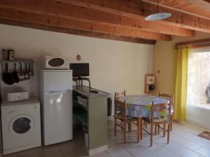 a kitchen with a table and a table and a laundry room at La Nichoule in Rosières