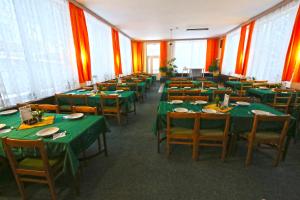 une salle à manger avec des tables et des chaises vertes dans l'établissement Hotel Astoria with private skibus, à Janské Lázně