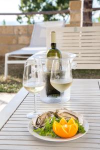 a plate of food with a bottle of wine and wine glasses at Petruso Resort in Balestrate