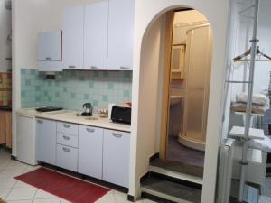 cocina con armarios blancos y puerta abierta en Sunset House, en Riomaggiore