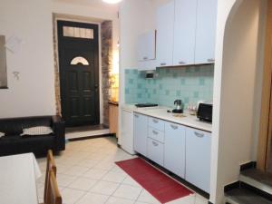 une cuisine avec des placards blancs et une porte noire dans l'établissement Sunset House, à Riomaggiore 28 autres photos