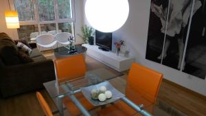 a living room with a glass table and orange chairs at Apartamentos Antares 1 in Milladoiro +48 photos