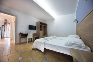 a white bedroom with a bed and a desk at Petruso Resort in Balestrate