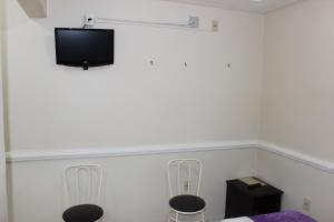 a room with two chairs and a tv on the wall at Hotel Lumem Taguatinga Sul in Taguatinga