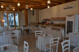 - une cuisine et une salle à manger avec des tables et des chaises blanches dans l'établissement Agriturismo Olistico Atman, à Monzambano