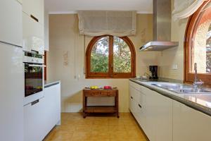 eine Küche mit weißen Schränken und einer Spüle und einem Fenster in der Unterkunft Angela in Tamariu + 10 Fotos