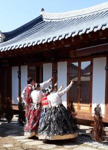 un groupe de personnes dansant devant un bâtiment dans l'établissement Sori poonggyung, à Jeonju