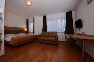 sypialnia z łóżkiem, kanapą i biurkiem w obiekcie Hotel Linde Stuttgart w Stuttgarcie