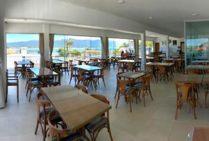 un restaurante vacío con mesas, sillas y ventanas en Hotel Pousada Santos, en Pinheira