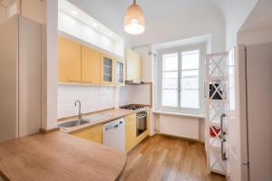 d'une cuisine avec des placards jaunes, un évier et une fenêtre. dans l'établissement Codelli Deluxe Fresco City Centre APP With Balcony, à Ljubljana