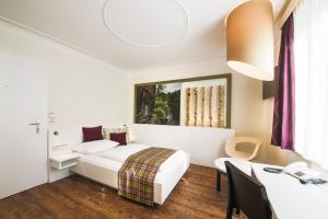 ブラウナウ・アム・インにあるHotel Mayrbräuのベッドとデスクが備わるホテルルームです。
