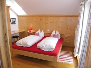 a bedroom with a red bed with white pillows at Landgasthof Fischbach in Wackersberg