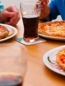 a table with plates of pizza and a glass of soda at Country Camp camping Nommerlayen in Nommern