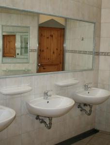 a bathroom with three sinks and a mirror at Country Camp camping Nommerlayen in Nommern