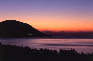a sunset over the water with a mountain in the background at Anassa in Polis Chrysochous