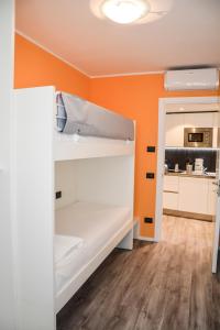 une chambre orange avec des lits superposés et une cuisine dans l'établissement Rivacentro, à Riva del Garda