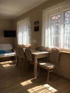 a room with a table and chairs and windows at Plażowa klatka 5P -wewnętrzne podwórko- Apartament 5P, piętro I in Rowy