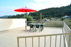 un patio con mesa, sillas y sombrilla en Casa Rebelo, en Cossourado