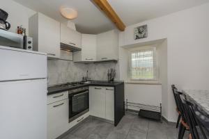 a kitchen with white cabinets and a stove top oven at Apartments Mijat in Novigrad Istria
