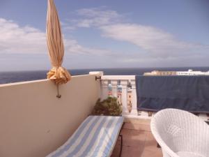 a balcony with an umbrella and chairs and the ocean at Arcoiris in Callao Salvaje