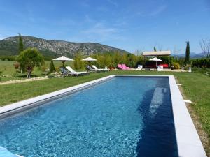 a swimming pool in a yard with chairs and umbrellas at Chambre d'hôtes du Mas de Longuefeuille in Malaucène