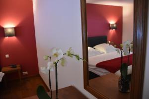 a mirror in a room with a bed and flowers at Hotel Le Moulin Simonis in Laforêt