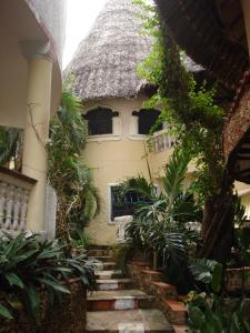 a house with a thatched roof with stairs in front at Coconut Village Beach Resort in Diani Beach