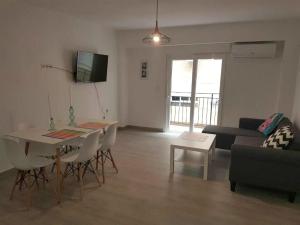 ein Wohnzimmer mit einem Tisch und einem Sofa in der Unterkunft Playa Precioso apartamento para familia con niños in San Juan de Alicante