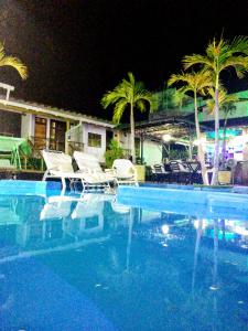 a swimming pool with chairs and palm trees at night at Jardín Del Duque Hotel Boutique in Santa Marta