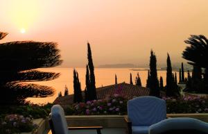 a sunset over the water with two chairs and trees at Anassa in Polis Chrysochous