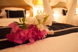 a bouquet of pink and white flowers on a bed at Casa Narrow Villa in Nembrala