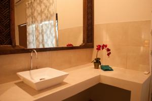 a bathroom with a sink and a mirror and flowers at Casa Narrow Villa in Nembrala