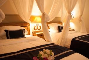 a bedroom with two beds with curtains and flowers on them at Casa Narrow Villa in Nembrala