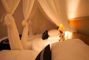 a bedroom with two beds with white drapes at Casa Narrow Villa in Nembrala