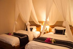two beds in a hotel room with white curtains at Casa Narrow Villa in Nembrala