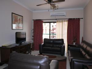 een woonkamer met lederen meubels en een flatscreen-tv bij Marina Condominium Holiday Homestay in Kota Kinabalu