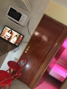 a wooden door in a room with red chairs and a television at Atico plaza San Martín/plaza mayor in León