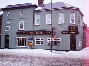 ein großes graues Gebäude mit einem Schild für das Schwimmhotel in der Unterkunft The Swan Hotel in Lydney