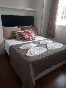 uma cama com duas toalhas em cima em Glamour Gramado Residence em Gramado